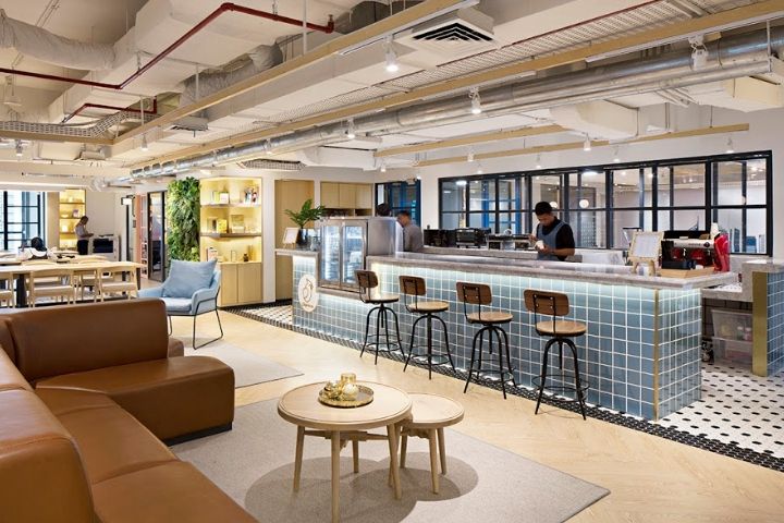 Modern coworking-miljö med loungemöbler och en bar i industriell stil.
