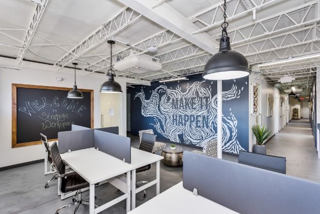 Modern coworking-miljö med skrivbord och inspirerande väggkonst.